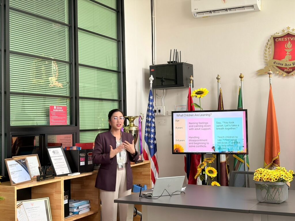 The Preschool Principal presenting to parents, with sunflowers on the table and beside the screen